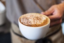 Nahaufnahme einer Person mit einer Tasse frischen Cappuccino. — Stockfoto