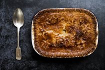 High angle view of freshly baked chicken pie and silver spoon. — Stock Photo