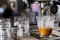 Primer plano de la máquina de café expreso comercial en la cafetería vertiendo café en vidrio . - foto de stock