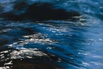 Abstract close-up of flowing river water with light reflection on surface. — Stock Photo