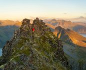 Человек поднимается на крутую вершину в зазубренном ландшафте острова Сенья, Тромс, Норвегия, Европа . — стоковое фото