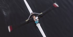 Vue aérienne du rameur en bateau à goélette simple en eau calme à mi-course, flou de mouvement . — Photo de stock