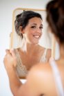 Portrait of smiling woman holding and looking in mirror. — Stock Photo