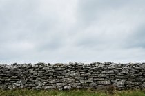 Old dry stone wall under cloudy sky, Cornwall, England, United Kingdom. — Stock Photo