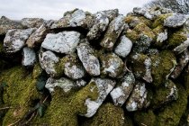 Nahaufnahme einer Trockenmauer mit Steinen, die teilweise mit Moos bedeckt sind, Kornmauer, England, Vereinigtes Königreich. — Stockfoto