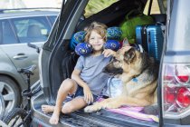 Junge im Grundalter mit Schäferhund und Reisekissen im Rücken eines Geländewagens. — Stockfoto
