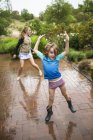 Niño de edad elemental con hermana adolescente bailando bajo la lluvia . - foto de stock