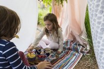 Little boy and girl playing in outdoor improvised tent — Stock Photo