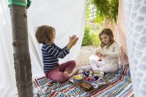 Bambino e ragazza che giocano nella tenda improvvisata all'aperto — Foto stock