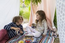 Мальчик и девочка играют в наружной импровизированной палатке — стоковое фото