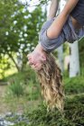Blonde teenage girl hanging upside down from tree. — Stock Photo