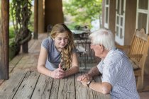 Adolescente loira conversando com o avô sênior . — Fotografia de Stock