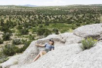Blonde teenage girl lying down on rock formation, Tsankawi Ruins, New Mexico, USA — Stock Photo