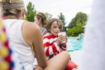 Kleiner Junge mit teen sister und mutter sitting von pool side. — Stockfoto