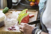 Nahaufnahme der Hände beim Schneiden von Wassermelonenscheiben in der Küche — Stockfoto