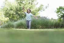 Happy little boy running on green lawn. — Stock Photo
