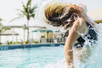 Ragazza bionda adolescente che salta fuori dalla piscina e lancia i capelli bagnati . — Foto stock