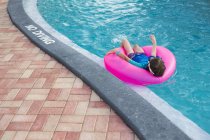 Мальчик в бассейне на розовом надувном кольце на воде . — стоковое фото