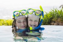 Ragazza adolescente bionda e elementare fratello in piscina sorridente . — Foto stock