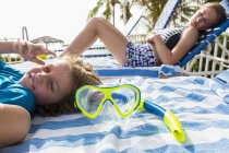 Snorkel mask on towel with children in background — Stock Photo