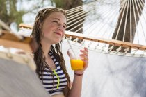 Blondes Teenager-Mädchen ruht in Hängematte und trinkt Fruchtgetränk. — Stockfoto