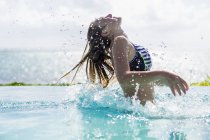 Adolescente loira na piscina infinita jogando cabelo molhado . — Fotografia de Stock