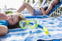 Brother and sister lying on sunbeds on tropical beach. — Stock Photo