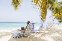 Дорослі жінки-виконавці використовують ноутбук на пляжі (острів Гранд-Кайман). — стокове фото