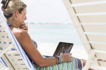 Ejecutiva femenina adulta usando computadora portátil en la playa, Isla Gran Caimán - foto de stock