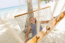 Teenage girl relaxing in hammock on tropical beach. — Stock Photo