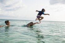 Взрослая женщина смотрит, как дети играют в океанской воде — стоковое фото