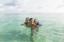 Mujer adulta parada en el agua del océano al atardecer con niños . - foto de stock