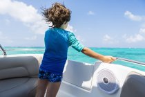 Мальчик на лодке смотрит на водное пространство океана, вид сзади . — стоковое фото