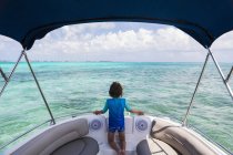 Мальчик на лодке смотрит на водное пространство океана, вид сзади . — стоковое фото