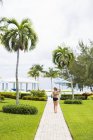 Rear view of teen girl walking to pool at resort. — Stock Photo