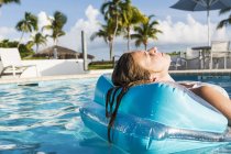 Teenage girl relaxing in floatie in swimming pool. — Stock Photo