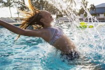Adolescente chica lanzando el pelo mojado en la piscina . - foto de stock