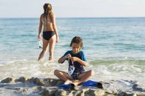 Little boy putting swim fins on sandy beach. — Stock Photo