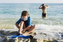 Little boy putting swim fins on sandy beach. — Stock Photo