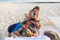 Madre con niños disfrutando de la playa al atardecer, Isla Gran Caimán - foto de stock