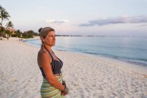 Mulher adulta olhando para o pôr do sol na costa do oceano, Grand Cayman Island — Fotografia de Stock