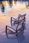 Sedie da spiaggia in piscina acqua al tramonto . — Foto stock