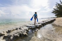 Bambino che cammina sulla formazione rocciosa con pinne, Grand Cayman Island . — Foto stock
