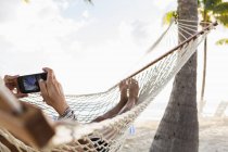 Frau entspannt sich in Hängematte mit Smartphone. — Stockfoto