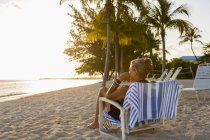 Взрослая женщина, сидящая в пляжном кресле на острове Кайман — стоковое фото