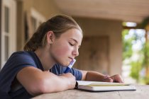 Teenage girl reading and writing in diary at home — Stock Photo