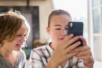Brother and sister holding smartphone and looking at screen. — Stock Photo