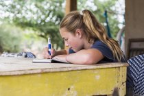 Menina adolescente lendo e escrevendo em diário em casa — Fotografia de Stock