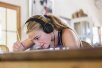 Adolescente em casa usando fones de ouvido como pintura — Fotografia de Stock
