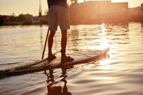 Homme debout sur le paddleboard sur la rivière à l'aube, recadré — Photo de stock